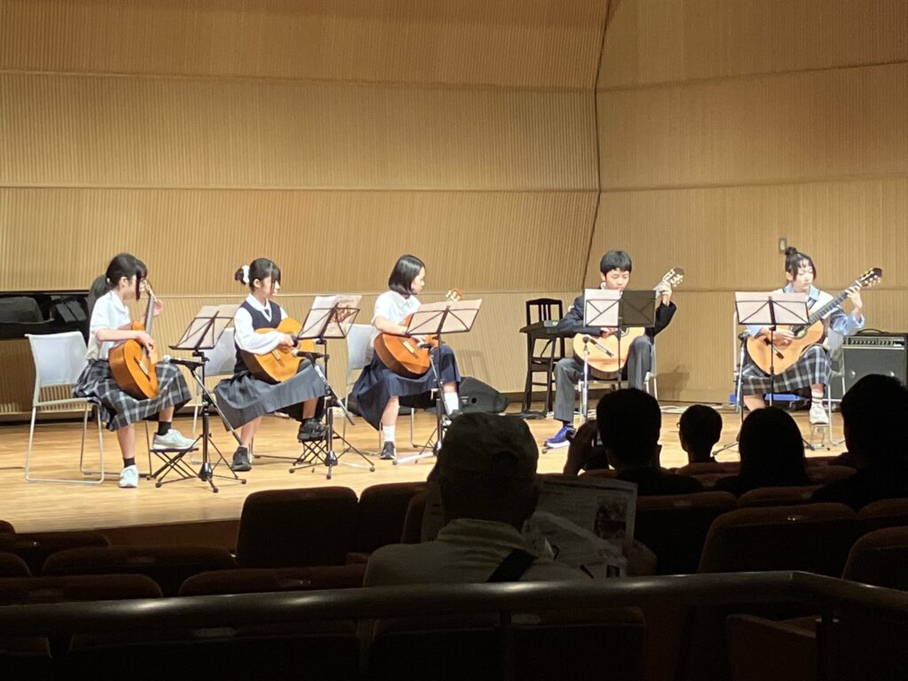 ステージでクラシックギターを合奏する5人
